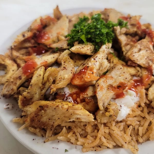 Jasmine Grill and Kabab's chicken shawarma with rice, red sauce, white sauce, and parsley.