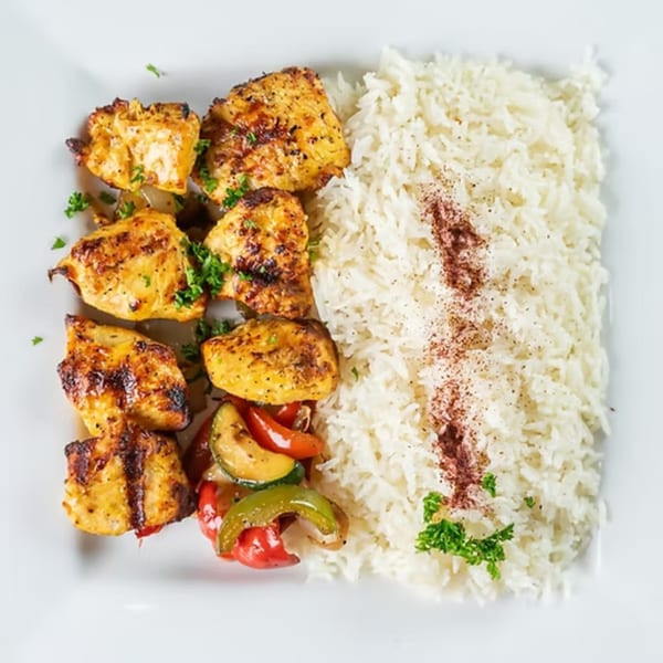 Jasmine Grill's chicken kabob with grilled vegetables and rice, garnished with sumac and parsley.